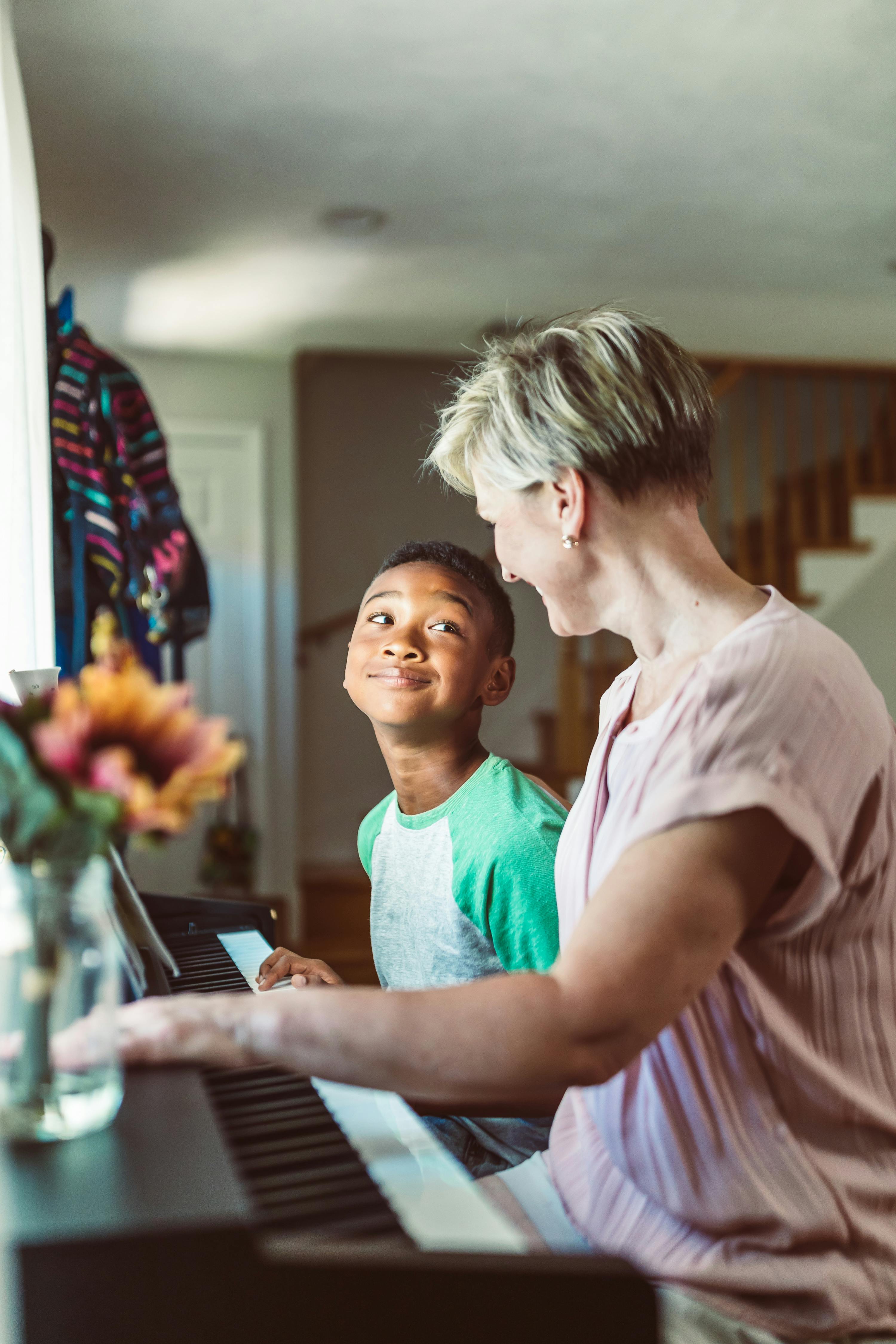 A lady teaches piano to a boy